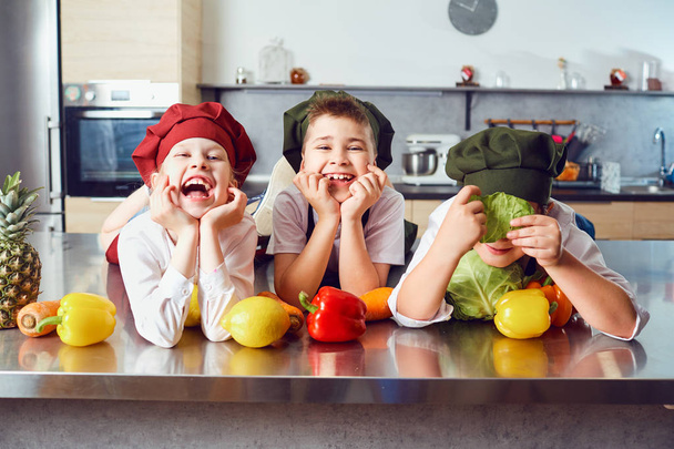 Funny children in the uniform of cooks in the kitchen. - Фото, изображение
