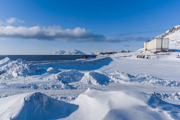 Landscape of the Russian city of Barentsburg on the Spitsbergen archipelago in the winter in the Arctic In sunny weather and blue sky - Fotó, kép