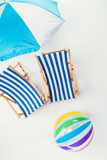 top view of beach umbrella, striped beach chairs and inflatable ball isolated on white - Foto, afbeelding