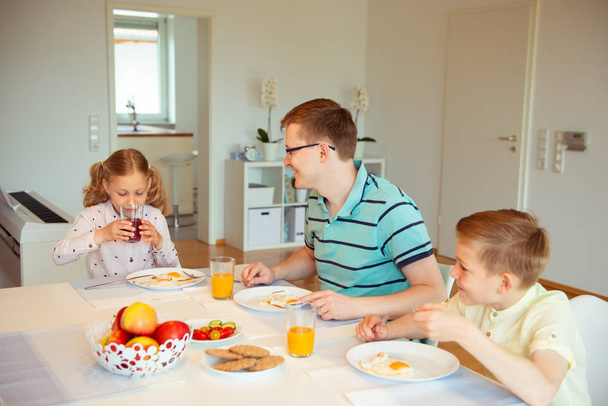 Szczęśliwy ojciec z jego cute dzieci rozmawia na śniadania w domu - Zdjęcie, obraz
