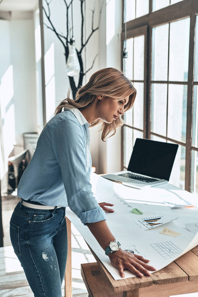blonde young woman working on blueprint in modern office  - Foto, Bild