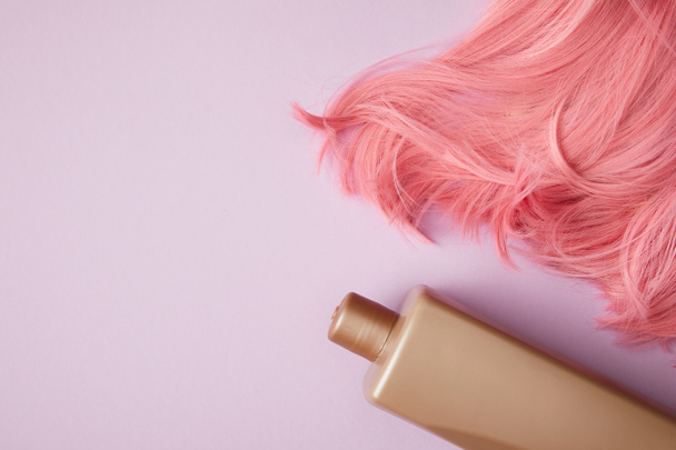 το Top view από φωτεινά ροζ περούκα και κενό δοχείο σε μωβ - Φωτογραφία, εικόνα