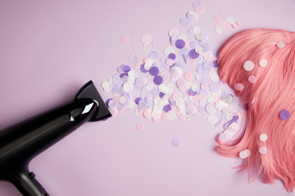vista superior de secador de pelo, confeti y peluca rosa en púrpura
 - Foto, imagen