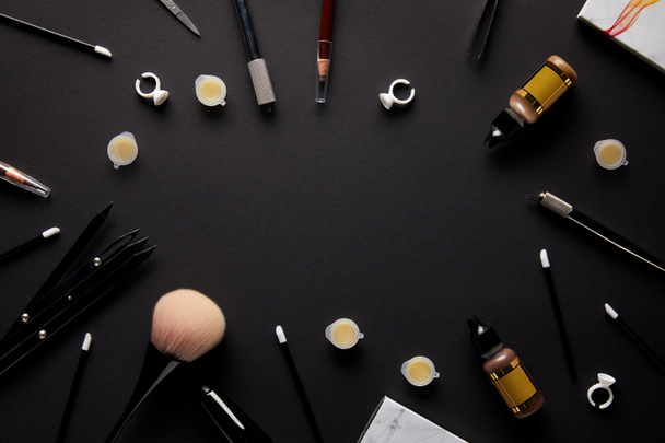 vue du dessus des outils pour le maquillage permanent sur table noire dans le salon
 - Photo, image