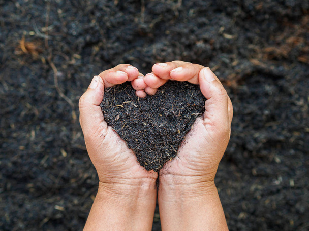 Eart day, save the earth, love concept. the woman hand holding a soil on ground blur background. - Valokuva, kuva