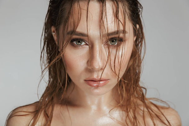 Close up fashion portrait of a topless sensual woman with makeup and wet hair posing isolated over gray background - 写真・画像