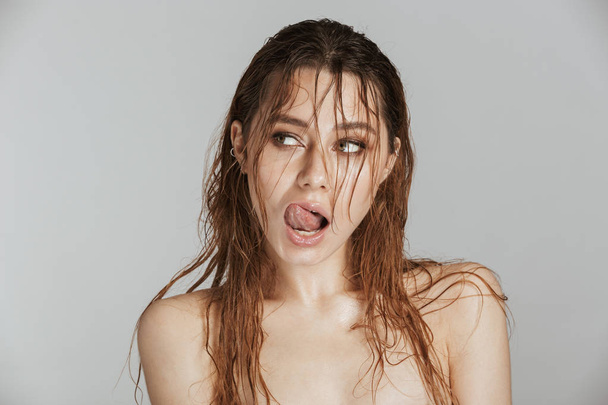Image of an amazing young beautiful woman with wet hair isolated over grey wall background looking aside licking her lips. - Фото, изображение
