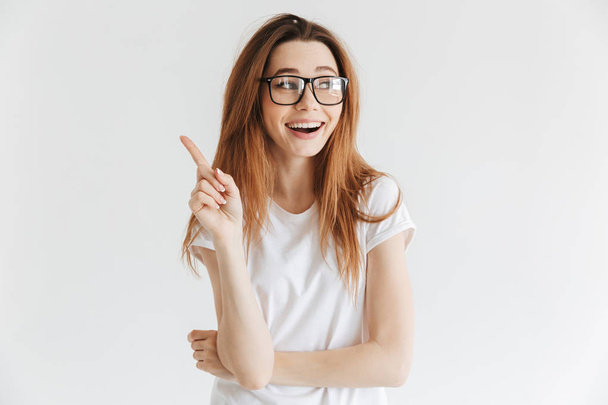 Happy woman in t-shirt and eyeglasses having idea and looking away over grey background - Foto, Imagen