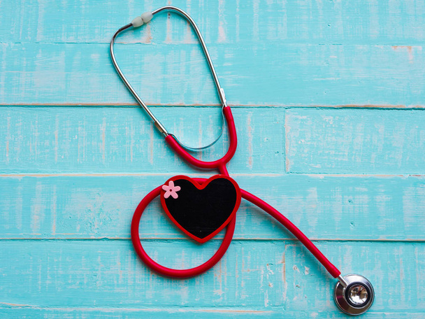 Κόκκινη καρδιά και στηθοσκόπιο σε μπλε φωτεινό φόντο ξύλινη. Υγειονομική περίθαλψη και ιατρική αντίληψη. - Φωτογραφία, εικόνα