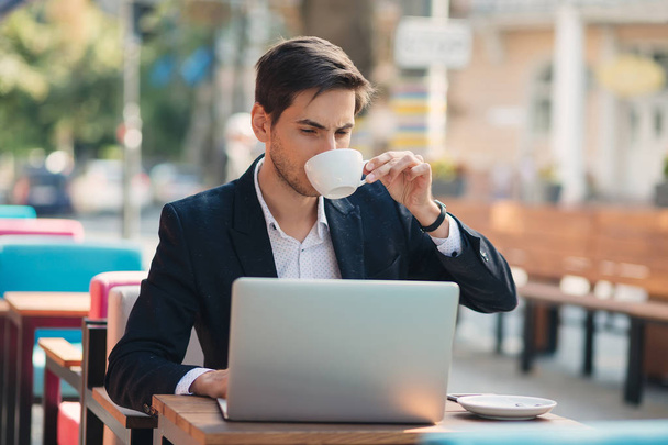Όμορφος νεαρός Απολαύστε καφέ εργασίας για φορητό υπολογιστή - Φωτογραφία, εικόνα