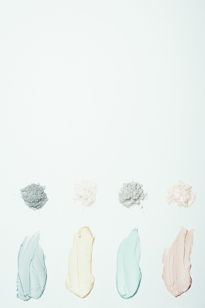flat lay with different clay powder and colorful clay mask smudges placed in row isolated on white surface  - Fotó, kép