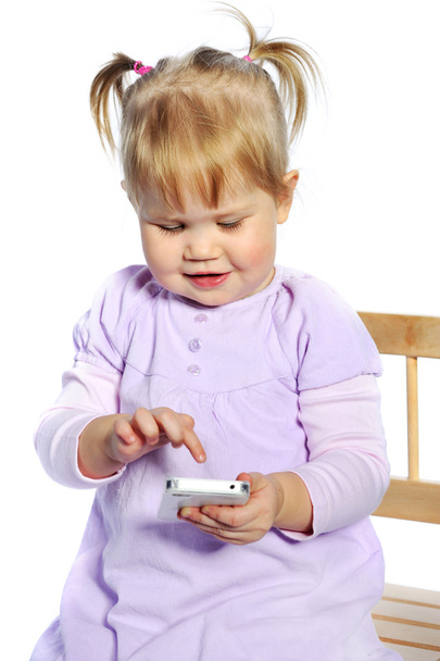 Suloinen pieni tyttö käyttää matkapuhelinta valkoisella taustalla
 - Valokuva, kuva