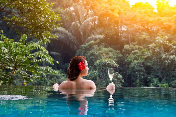 girl in the tropic jungle pool with a glass of champagne - Photo, Image