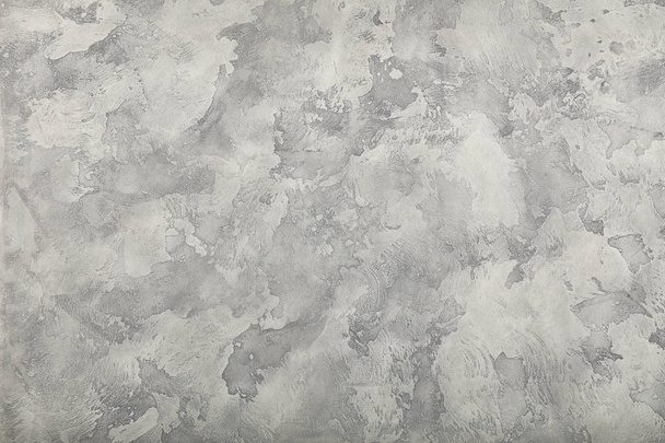 Grunge grey faded uneven old aged daub plaster wall texture background with stains and paint strokes, close up - 写真・画像