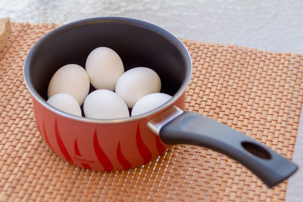 een paar gekookte eieren in een pan in de zon - Foto, afbeelding