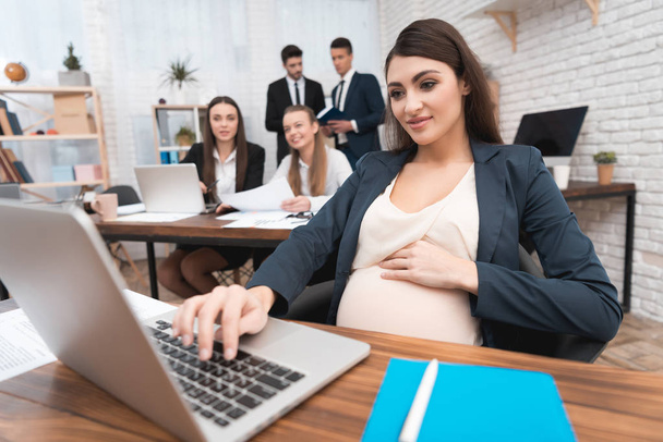 Pregnant woman typing on laptop keypad in office - Fotoğraf, Görsel