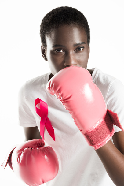 young woman with ribbon on t-shirt boxing and looking at camera isolated on white, breast cancer concept - Fotó, kép