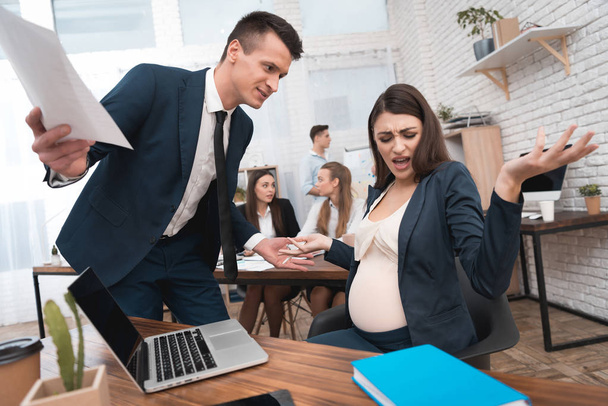 Angry young man in suit screaming at pregnant woman in office - Фото, зображення