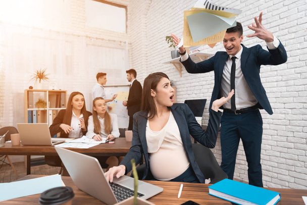 Angry young man in suit screaming at pregnant woman in office - Foto, afbeelding