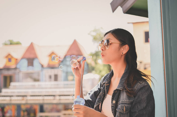 Travel Concepts. Beautiful girl is playing soap bubble fun. Asian girls are relaxing travels. Asian girls blowing bubbles into the air. Beautiful girl takes a break in playing bubble activities. - Photo, Image
