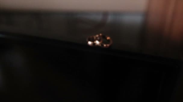 Красивая камера полет на обручальные кольца, которые лежат на углу с лакированным покрытием
 - Кадры, видео