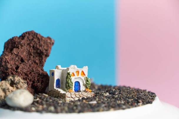 animiertes Modell eines griechischen Hauses auf einem Felsen auf neonrosa Hintergrund. - Foto, Bild