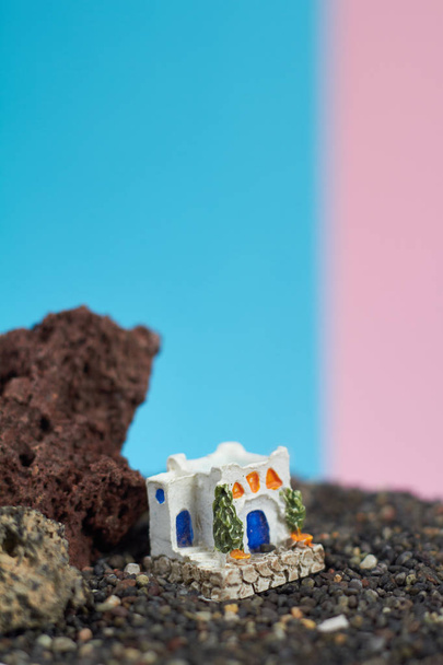 Ζωντανεψοντα πρότυπο των ένα ελληνικό σπίτι πάνω σε ένα βράχο σε ένα neon και ροζ φόντο. - Φωτογραφία, εικόνα