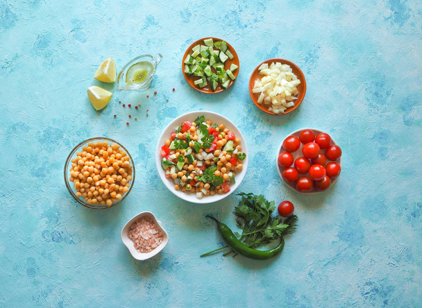 Csicseriborsó saláta. Szeletelt zöldségek és a csicseriborsó másol hely kék háttérrel. - Fotó, kép