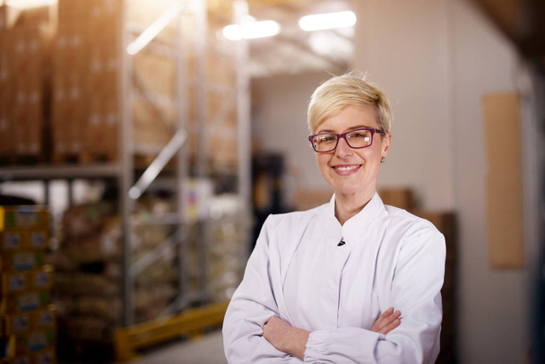  jovem trabalhador feminino profissional feliz em roupas estéreis brancas na sala de armazenamento de fábrica
 - Foto, Imagem
