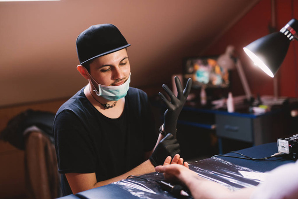 jonge gericht tatoeëerder inkt arm van klant - Foto, afbeelding