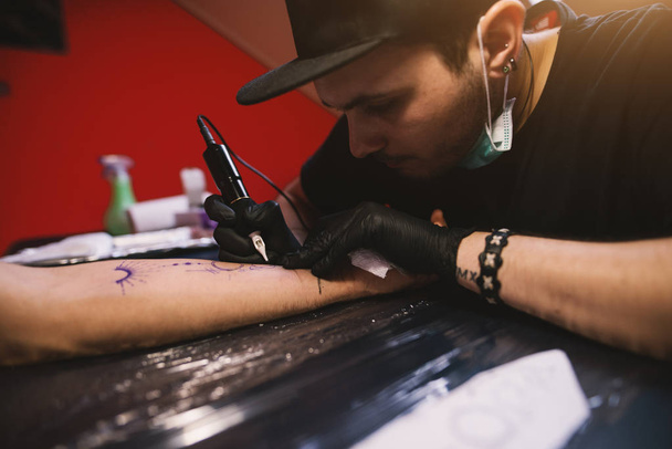 joven centrado tatuaje artista entintado brazo de cliente
 - Foto, imagen