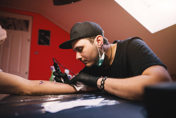 giovane tatuatore focalizzato braccio inchiostratore del cliente
 - Foto, immagini