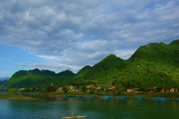 Barcos de madeira azuis no grande rio em frente a montanhas verdes em Phong Nha - Ke Bang, Patrimônio Mundial da UNESCO na província de Quang Binh, localizada no Vietnã
 - Foto, Imagem