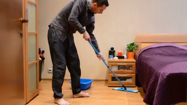 Młody człowiek myje podłogi mopem - Materiał filmowy, wideo