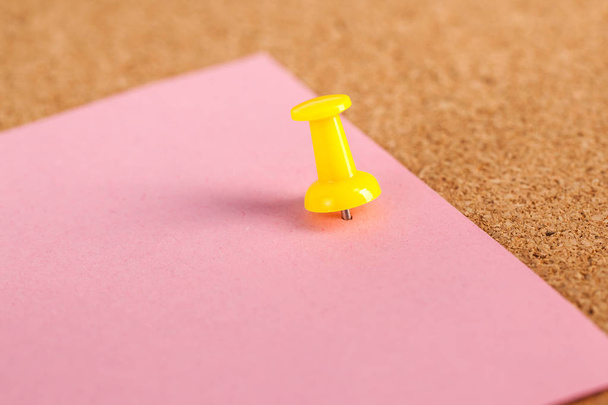 Papier rose pincé avec une pointe jaune sur fond de carton de liège brun
. - Photo, image