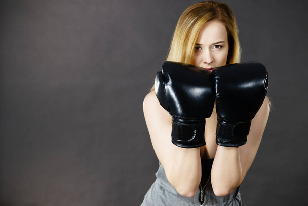 Sportsmanship fairplay and strong body. Young woman fighting boxing. Blonde girl wearing black punch gloves. Sport and fitness, power, exercising. - Fotografie, Obrázek
