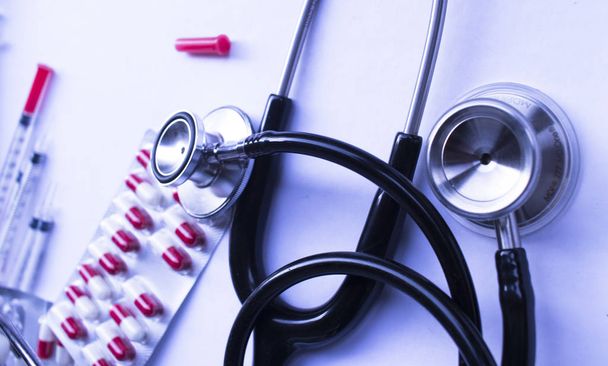 Medical prescription drug pills blister pack of red and white medication capsules syringe and doctors stethoscope. - Photo, Image