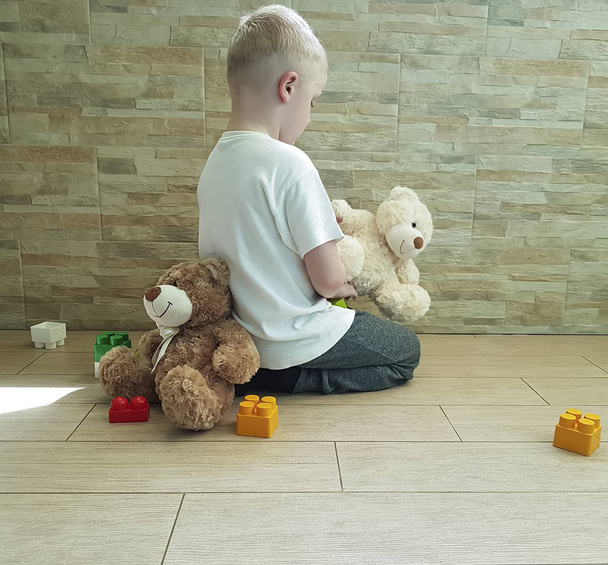 triste bambino con un orsacchiotto seduto sul pavimento che protesta le emozioni
 - Foto, immagini