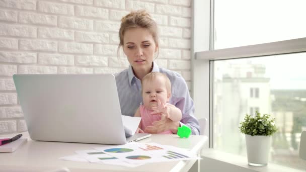 Nainen, jolla on vauva, ei keskittynyt töihin. Business äiti näköinen asiakirjoja - Materiaali, video