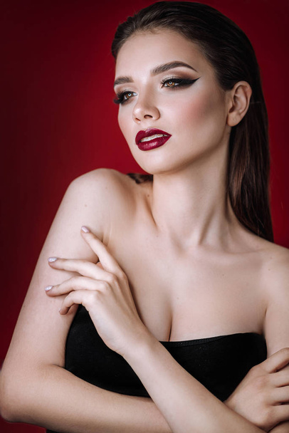 fashion portrait of a girl with makeup on a red background - Zdjęcie, obraz