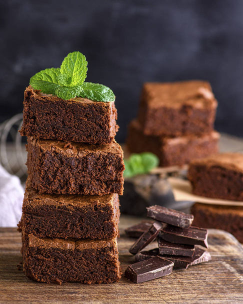 square pieces of baked brownie lie in a pile on a wooden table, close up - Photo, Image