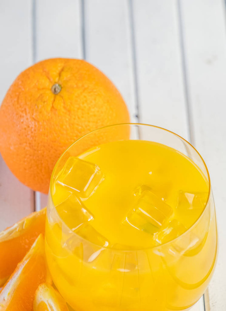 Cold fresh orange juice and fruits on wooden table. - Fotó, kép