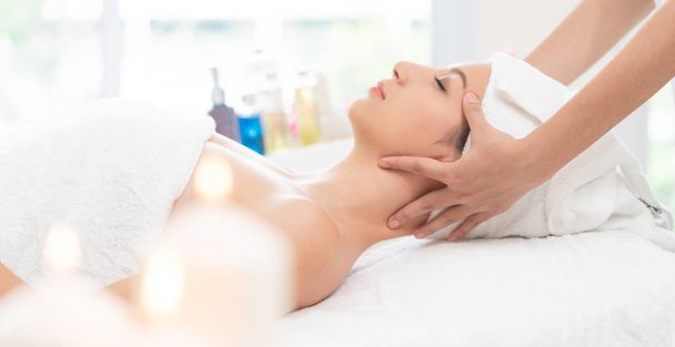 Relaxed woman lying on spa bed for facial and head massage spa treatment by massage therapist in a luxury spa resort. Wellness, stress relief and rejuvenation concept. - Photo, Image