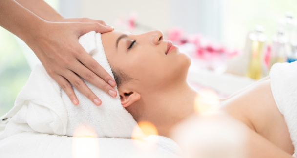 Relaxed woman lying on spa bed for facial and head massage spa treatment by massage therapist in a luxury spa resort. Wellness, stress relief and rejuvenation concept. - Zdjęcie, obraz
