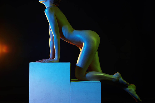 ヌードの女性、カラフルな明るいライト スタジオでポーズをとるします。キューブの女の子のキラキラの光沢のある裸体 - 写真・画像
