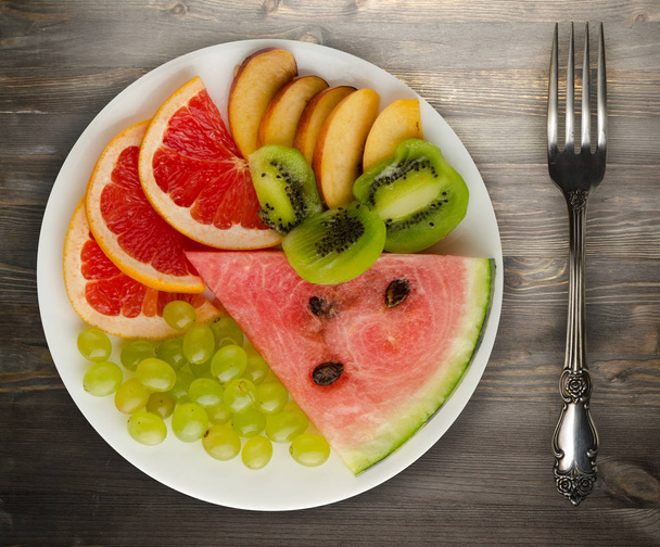 sliced fruit on a wooden background. sliced fruit on a plate - Fotoğraf, Görsel