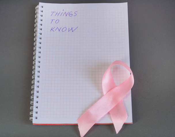Co trzeba wiedzieć jest napisane w Notatniku z różową wstążką świadomości raka piersi. - Zdjęcie, obraz