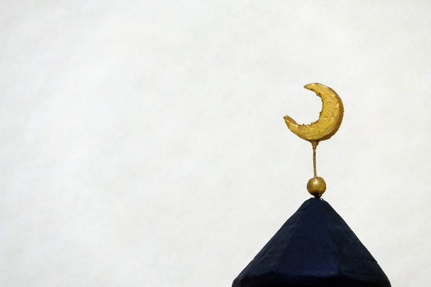 Iszlám kultúra és vallás kézzel jelképe. Crescent, arany színű, fekete felső minaret. Közelről. Másolja a hely. Világos háttér. - Fotó, kép