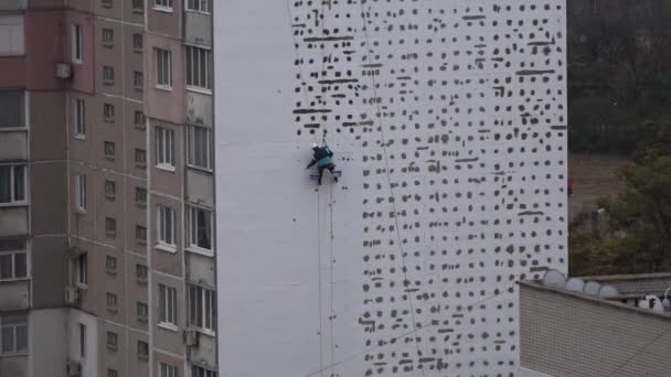High-altitude work. The man works on high-rise works cladding, plastering of the house. Warming of the facades of high-rise buildings.Warming of the facades of high-rise buildings.High-altitude work in a residential area.Warming houses. - Footage, Video