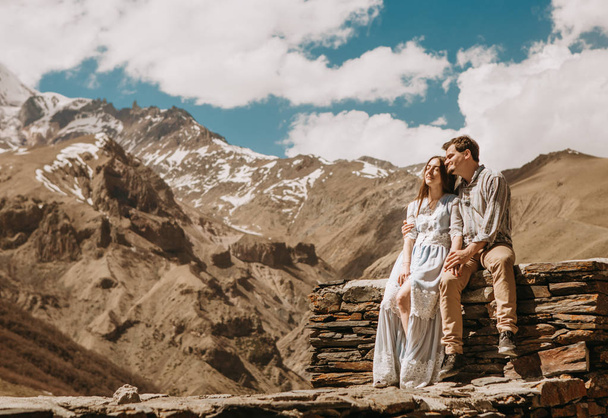 loving couple in the mountains watching and dreaming sitting on a stone fence - Foto, Bild